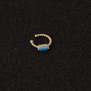 Χρυσό σκουλαρίκι ear cuff σχήματος U με μπλε ζιργκόν σε μαύρη επιφάνεια