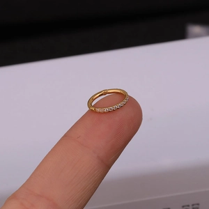 Detail of a gold stainless steel hoop earring with side-set cubic zirconia on a fingertip