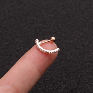 Detailed view of rose gold curved stud earring with white zircon inlay held by hand