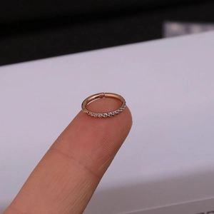 Macro shot of a rose gold seamless hoop ring with side-set zircon crystals on a fingertip