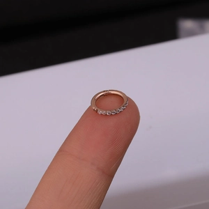 Macro shot of rose gold nose ring with small cubic zirconia stones on fingertip