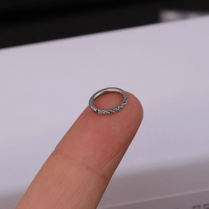 Macro view of silver stainless steel clicker ring with side-set cubic zirconia stones