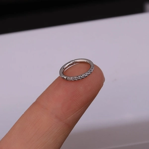 Detail view of small stainless steel hoop with side-set cubic zirconia on a fingertip