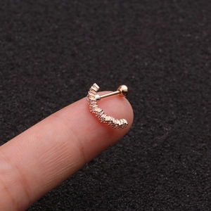 Macro shot of rose gold curved bar ear stud with zircon stones on a fingertip