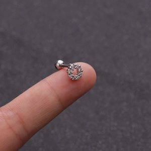 Dettaglio macro di un piercing in acciaio argentato con cerchio di zirconi sulla punta del dito