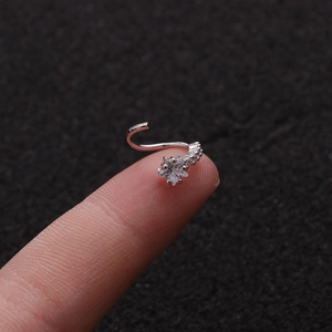 Primer plano de un piercing de nariz plateado con forma de estrella y circonita en el dedo