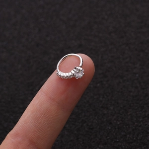 Piercing de nariz corazón plateado con circonitas brillantes sobre fondo oscuro