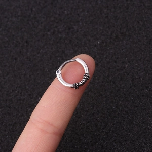 Close-up of vintage silver twisted nose ring with retro spiral texture held on fingertip