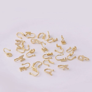 Detalle de piercings falsos dorados con micro-pavé de circonitas sobre fondo lila