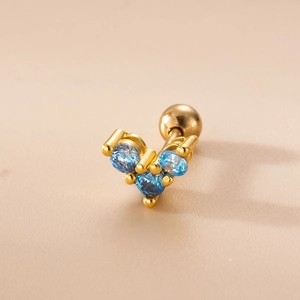 Macro shot of gold ear piercing with heart-shaped blue zircons and screw ball back