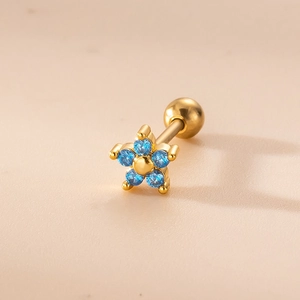 Detailed macro shot of a gold flower cartilage stud with five light blue zircon petals