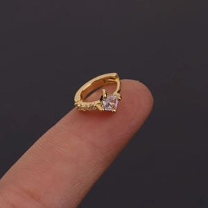 Vue macro d'un mini anneau doré avec zircon carré sur le bout d'un doigt pour l'échelle