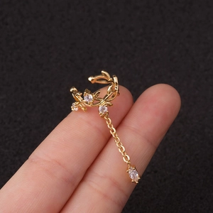 Λεπτομερής όψη χρυσού ear cuff με φύλλα, ζιργκόν πέτρες και μια λεπτή κρεμαστή αλυσίδα