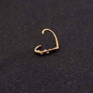 Polierter goldener herzförmiger offener Ring Piercing-Schmuck auf dunklem Hintergrund