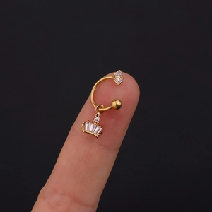 Dettaglio macro di un anello a ferro di cavallo dorato con ciondolo a corona sul dito