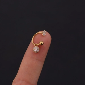 Dettaglio di un orecchino a forma di C placcato oro con pendente a fiore in zircone