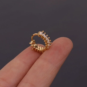 Vue détaillée d'une mini créole dorée avec zircons marquise sur le bout du doigt