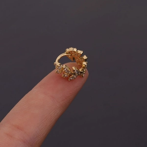 Vue macro des boucles d'oreilles feuille d'or avec pierres de zircon blanc sur un doigt