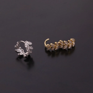 Boucles d'oreilles feuille or et argent avec zircons brillants sur fond noir mat