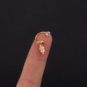 Dettaglio ravvicinato di un piercing a foglia dorata con zircone lucido e micro-pavé di cristalli