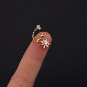 Dettaglio di ear cuff a stella dorata con cristalli di zircone sulla punta del dito
