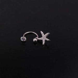 Dettaglio macro del piercing in acciaio con zircone e ciondolo a stella marina
