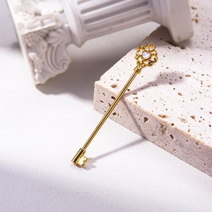 Detalle de piercing industrial dorado en forma de llave con incrustación de opalo
