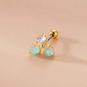 Dettaglio macro di piercing dorato con zircone e pietre di opale verde menta