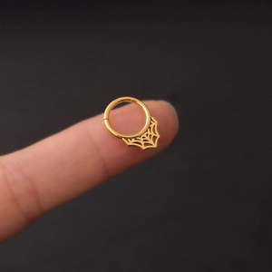 Anneau de septum en acier doré avec toile d'araignée présenté sur le bout du doigt