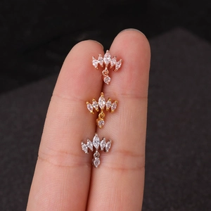 Gros plan de trois boucles d'oreilles couronne en zircon, or rose et argent sur les doigts
