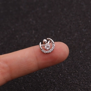 Detailed close-up of a silver crescent moon tragus piercing stud with zircon on a fingertip