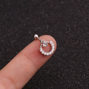 Detail view of heart-shaped zircon piercing earring held for scale against dark backdrop