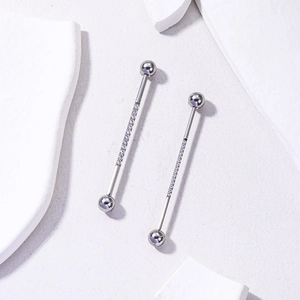 Detailed macro view of silver stainless steel industrial piercing bar with zircon crystals