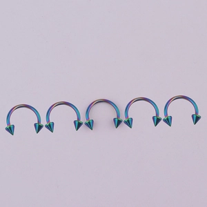 Detailed close-up of five rainbow 316L stainless steel horseshoe rings with spike ends