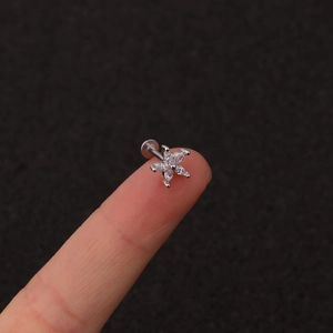 Macro view of tiny silver five-petal flower labret stud with white marquise zircons