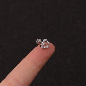 Macro detail of a silver heart-shaped ear piercing stud with micro-set zircon crystals