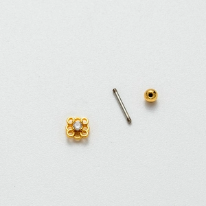 Disassembled view of gold flower cartilage stud with zircon center and threaded back