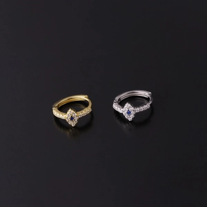 Detailed view of gold and silver huggie earrings with blue zirconia and diamond pattern