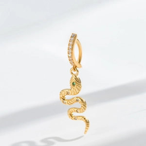 Macro detail of a golden snake pendant with sparkling zircons and a green gemstone eye