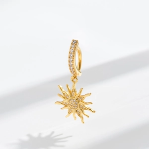Macro detail of sun pendant belly ring with pavé-set cubic zirconia and golden finish
