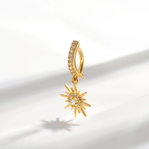 Macro shot of gold sunburst navel piercing pendant with sparkling cubic zirconia crystals
