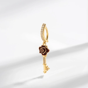 Detailed close-up of a vintage golden navel piercing with a red rose and key pendant