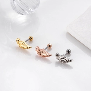 Detalle de pendientes de cartílago en forma de ala en oro y plata con circonita