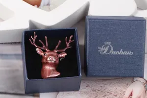 Detail of red-brown deer head brooch with sparkling rhinestone eyes in a blue gift box