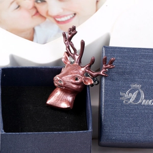 Detailed view of a vintage copper stag head brooch with a red rhinestone eye in a blue gift box