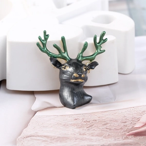 Detailed macro view of the 3D reindeer head brooch with green antlers and gold plating