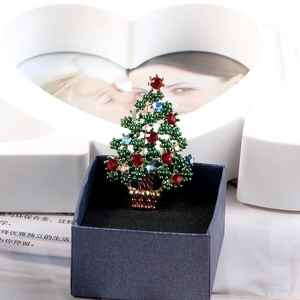 Detailed close-up of a Christmas tree brooch with colorful rhinestones in a blue velvet box