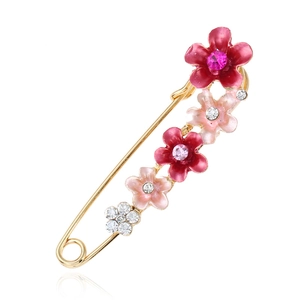 Broche épingle dorée élégante avec fleurs en émail rose et strass brillants sur blanc