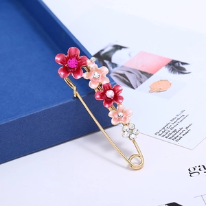 Détail d'une broche épingle à nourrice fleurie avec pétales en émail coloré et cristaux
