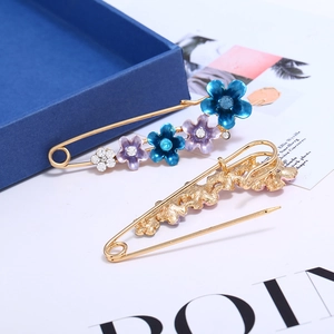 Vue détaillée d'une broche fleurie en émail avec strass et épingle dorée au dos